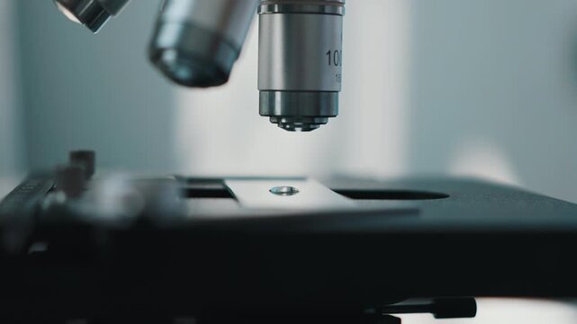 Microscope objective lens above laboratory sample slide close up