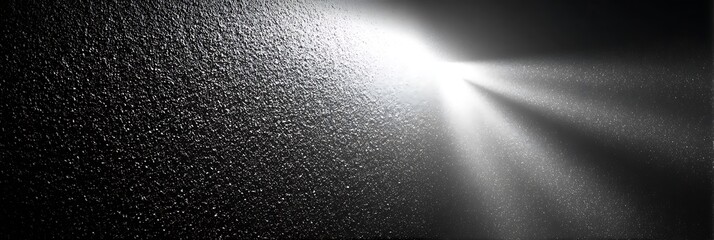 Abstract dark grainy surface texture illuminated by intense bright light beams shining diagonally and creating deep shadows in a high contrast modern environment © Strother