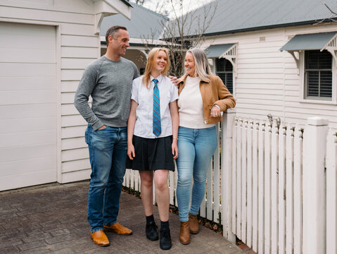 Happy family standing outside the white picket fence of their new home