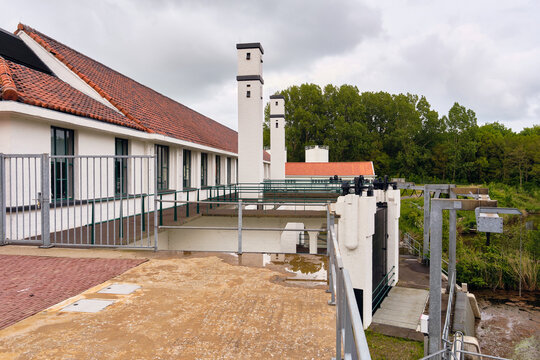 Wieringerwerf, Netherlands - 17 May 2026: View of the Gemaal Leemans pumping station featuring its white facade, red tiled roof, and tall chimneys under a cloudy sky.