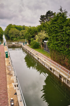 Wieringerwerf, Netherlands - 17 May 2026: View of Gemaal Leemans lock system with concrete walls, metal railings, and lush green trees under a cloudy sky.
