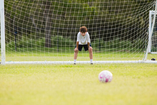 Young soccer player on defensive stance in front of soccer goal net during penalty kick