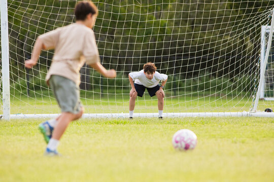 Young soccer player on defensive stance in front of soccer goal net during penalty kick