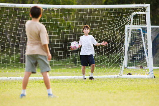 Young soccer player holding the soccer ball in front of soccer goal net during penalty kick