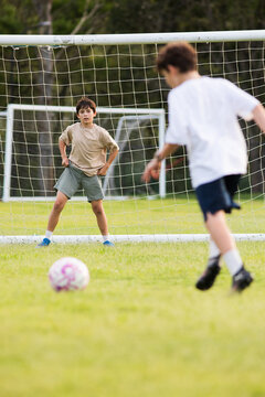 Young soccer player on defensive stance in front of soccer goal net during penalty kick