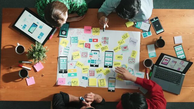 Professional developer team sharing idea of Ux Ui design by using mind map. Top down view of group of business people working together to brainstorm or plan mobile phone interface app. Convocation.
