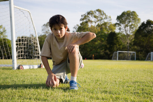 Young boy kneeling with one knee on grassy soccer field