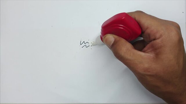 Hand Using Correction Fluid to Erase Writing on Paper