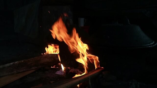The large fire seen is produced from burning firewood in a traditional stove for cooking using traditional methods.