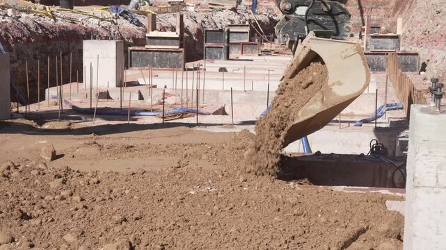 Heavy machinery excavator dumping soil into a deep foundation pit at a construction site, infrastructure development and urban engineering industry