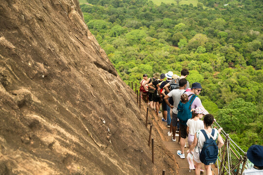 Sri Lanka - 21 February 2026: View of tourists climbing the steep metal stairs of Sigiriya Rock surrounded by lush tropical jungle.