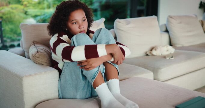 Sad, child and thinking on couch, home and girl with low self esteem from bullying and bad memories. Remember, trauma and kid with anxiety, loneliness and reflection on insecurity or mental health