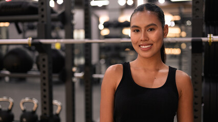 Fototapeta premium Asian Thai Isan Woman Smiling at Gym During Night Workout