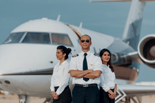 Pilot and flight crew standing confidently in front of a private jet ready for business travel