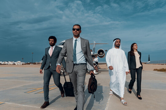 Business executives and diverse team walking confidently from a private jet on an airport tarmac