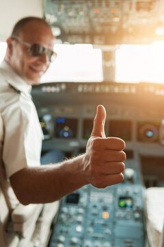 Pilot giving a thumbs up in the cockpit of a commercial airplane with sunlit controls
