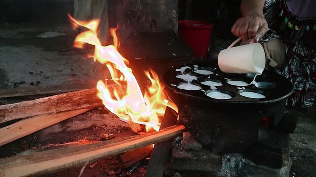 A traditional cooking method for snacks that uses a traditional molded frying pan and pieces of wood placed underneath to produce a large fire and smoky aroma in the resulting snack.