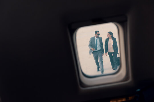Business colleagues walking to plane viewed through an airplane window during business travel