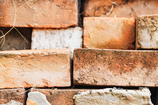 Close-up texture of weathered red bricks stacked unevenly, showing rough surfaces and age