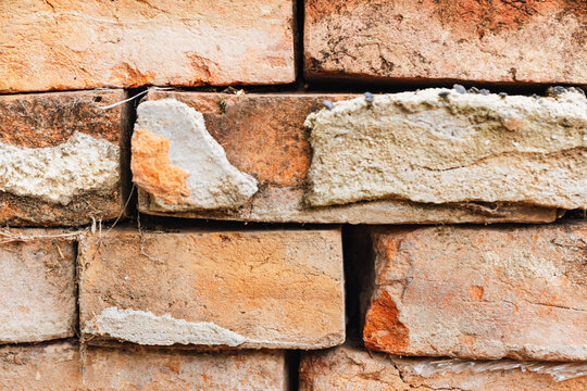 Close-up texture of weathered, aged red bricks with crumbling mortar and visible imperfections
