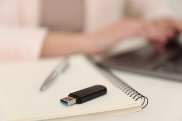 Fototapeta premium Woman with USB flash drive working on laptop at desk, selective focus