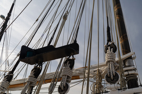 Four wooden deadeye blocks with standing rigging and white hull on a classic sailing ship, horizontal view