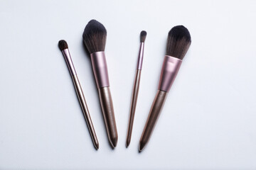 Obraz premium Set of makeup brushes on light background, flat lay