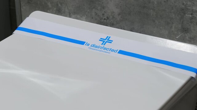 Small paper ribbon with printed note confirming disinfection rests on toilet lid. Inscription serves as proof of sanitary maintenance
