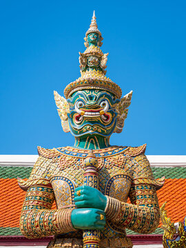 A green-faced yaksha guardian Thotsakan against blue sky at Wat Phra Kaew, Grand Palace, Bangkok, Thailand.
