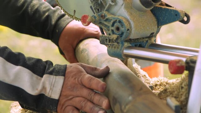 Skilled artisan meticulously smoothing round timber with hand and tool