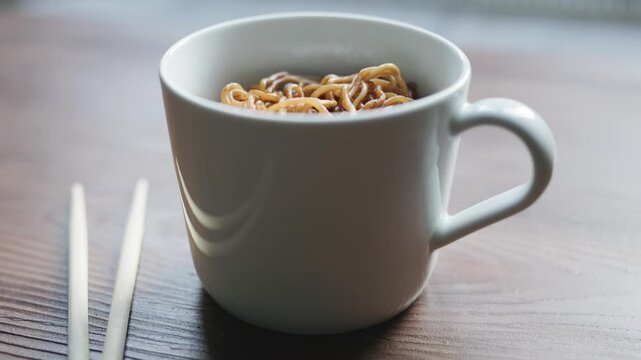 Close-up of instant noodles with hot water in a white cup