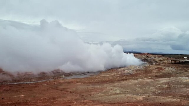 Volcanic landscape in Iceland showing a geothermal area with fumaroles emitting hot steam and sulfurous gases on a cloudy day
