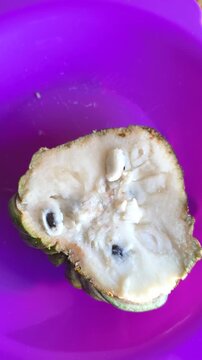 Close Up of Fresh Atemoya Fruit Cut in Half on Vibrant Purple Plate in 4K. 