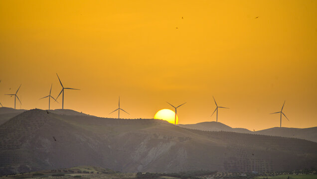 Wind turbines in mountainous region landscape in Taza, Morocco during dusk with setting sun, renewable energy for clean environment