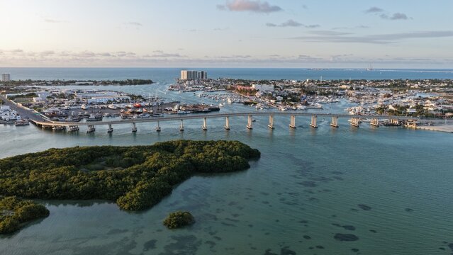 Aerial view of the Yucalpeten bridge spanning the waterway near the marina and lush mangroves under a clear sky in Progreso, Yucatan, Mexico.