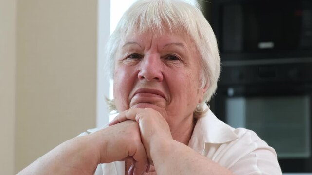 Smiling senior woman resting chin on hands looking forward with calm expression. Concept of aging well and retirement