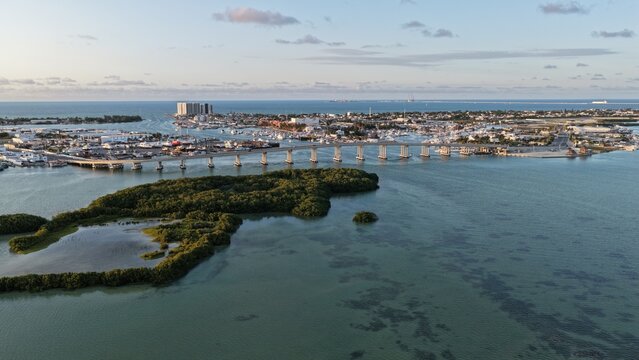 Aerial view of the Yucalpeten bridge spanning over the turquoise lagoon waters with lush mangroves and the coastal skyline under a soft sky Progreso, Yucatan, Mexico.