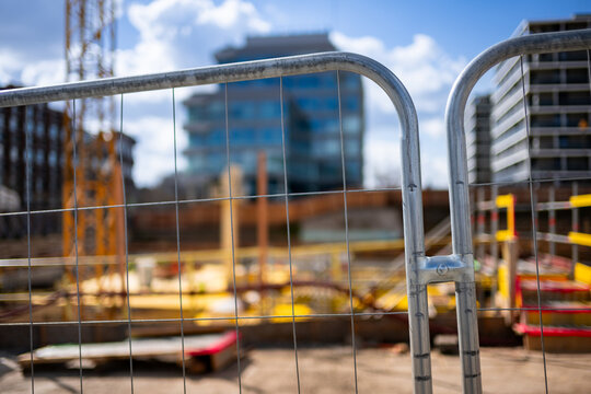 Blurred construction site through wire fence - abstract view of development in progress.