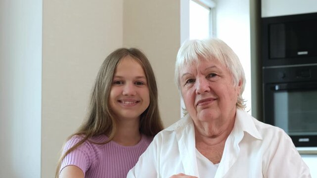 Portrait of smiling teenage girl and senior woman looking at camera at home. Concept of family love and happiness