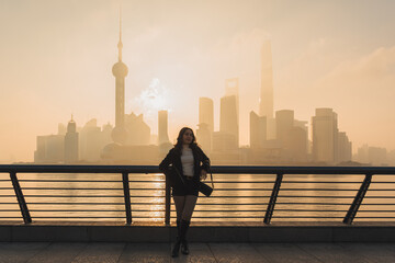 Obraz premium Female tourist admiring Oriental Pearl Tower and Shanghai financial skyscraper in golden morning at China