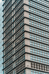 Fototapeta premium Modern highrise office building corner with repeating blue glass windows pattern