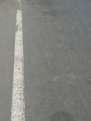 Fototapeta premium White solid road marking line on a gray asphalt street surface. 