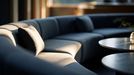 Obraz premium Warm light gently fills a sleek lounge area, highlighting a curved sofa and elegant tables. This inviting spot offers a perfect backdrop for relaxation and social gatherings