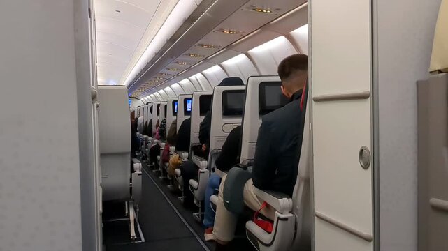 Airplane seat walkway, passengers awaiting in their seats