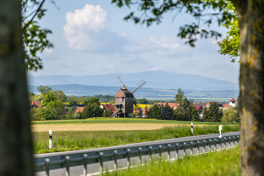 Eine deutsche Bockwindm&uuml;hle auf einem Feld mit Aussicht auf den Brocken im Harz
