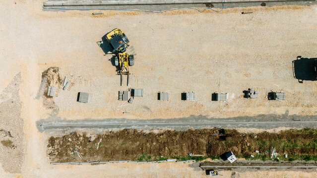 Aerial view of a yellow forklift moving materials at a construction site with stacks of bricks on gravel ground Pancevo, Vojvodina, Serbia.