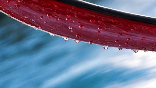 waterski. Close-up of a red waterski underside with water droplets on a blurred blue background. mobility guides, transit brochures, designed for transport & logistics marketing.