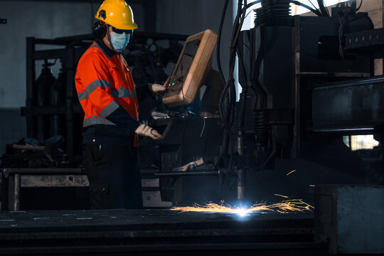 Smart industrial manufacturing automation technology concept. Professional operator worker controlling cnc plasma cutting machine for heavy steel metal fabrication process in commercial factory.