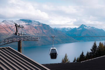 Queenstown, New Zealand: glass gondola cable car cabin suspended on wires over Lake Wakatipu, snow capped alpine mountain range travel background. © pam