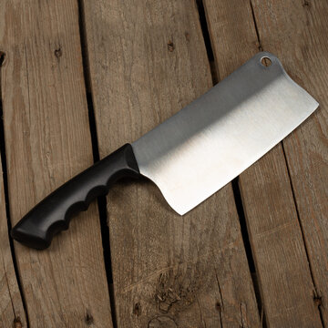 Heavy duty meat cleaver butcher knife on rustic wooden background, professional kitchen chopper tool